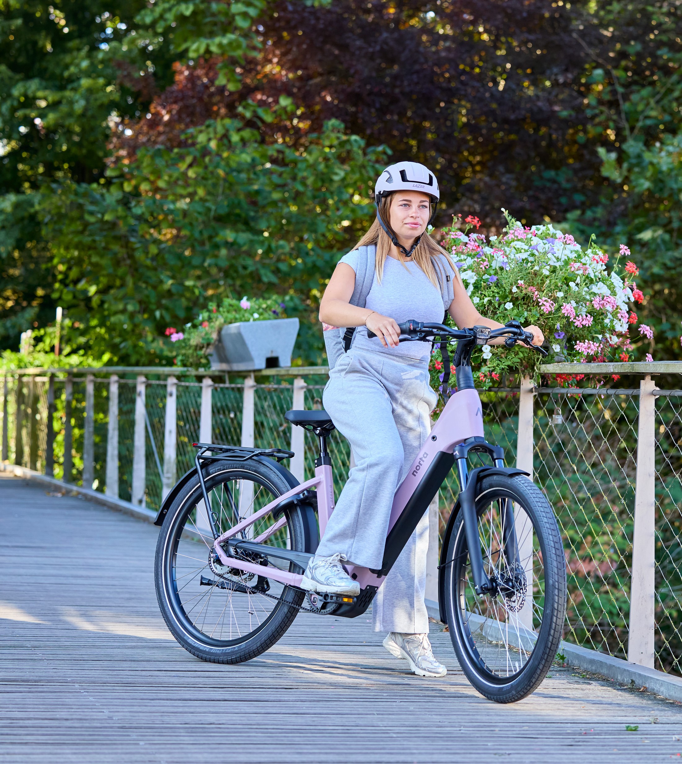 Vrouw op een Norta B-3030 elektrische fiets op een brug in een groene omgeving